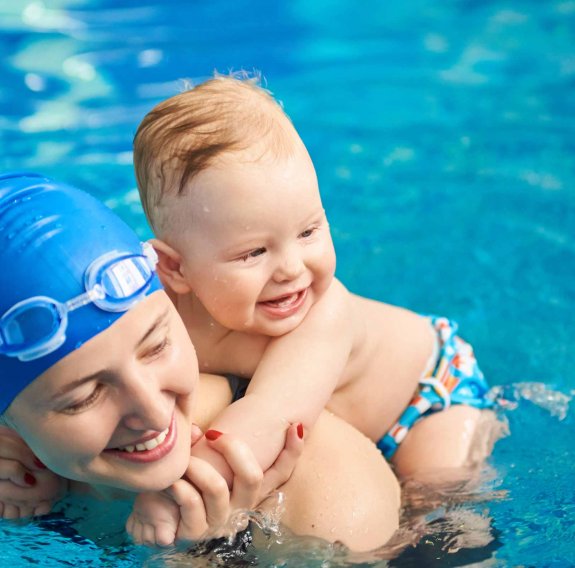 Mama mit ihrem Baby auf dem Rücken im Wasser