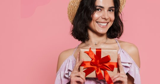 Eine lächelnde Frau präsentiert eine Geschenkbox