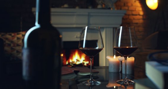 Zwei Rotweingläser stehen auf dem Tisch und Kamin ist im Hintergrund