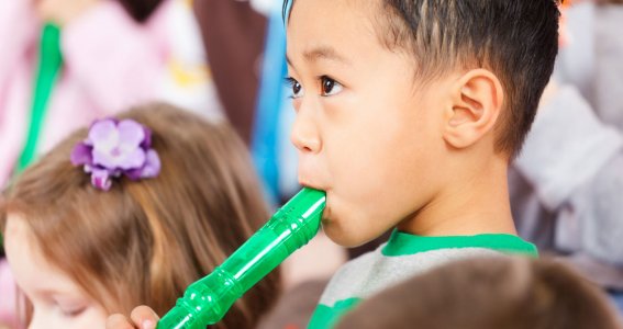 Kinder spielen bei der musikalischen Früherziehung Flöte 