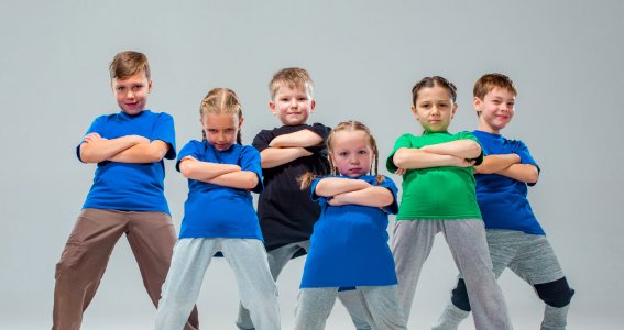 Eine Gruppe von Kindern mit grünen und blauen T-shirts posiert in Hip Hop Tanzformation