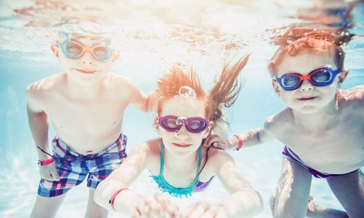 Schwimmen lernen für Kinder bei learn2swim in München Drei Kinder tauchen mit Schwmmbrille