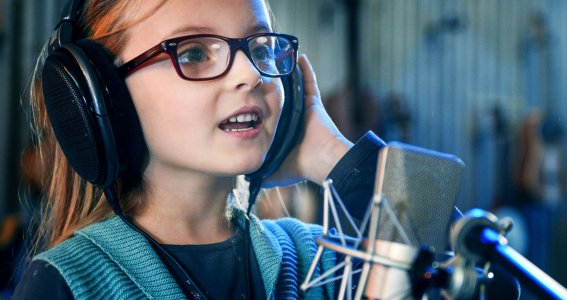 Kind singt mit Kopfhörern und Mikrophon