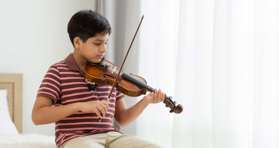 Junge spielt auf der Geige im Sitzen