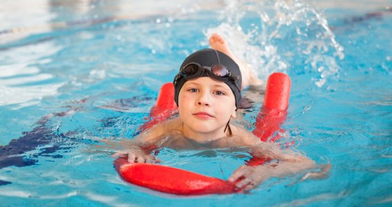 Junge schwimmt mit einer roten Schwimmnudel