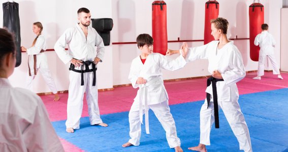 Zwei Jugendliche trainieren Abwehrtechniken des Taekwondo in einer Sporthalle