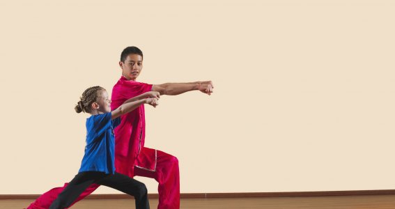 Kung Fu Training mit einem Jungendlichen und einem jungen Mädchen in chinesischer Kleidung