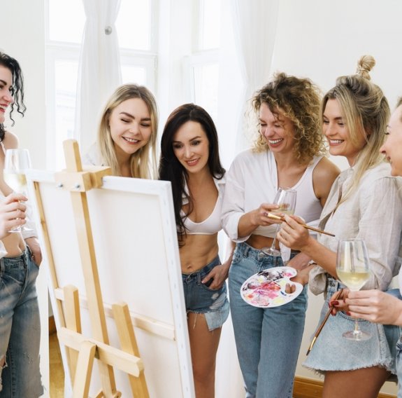 Frauen stehen vor einer Leinwand und malen